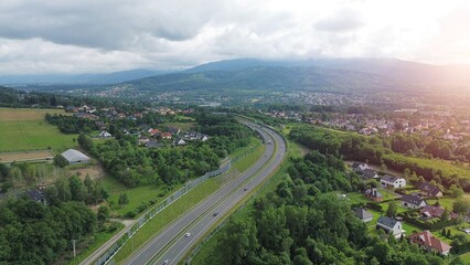 Winding road through green landscape with fields and houses