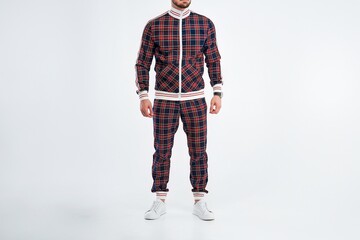 Model in plaid tracksuit standing against white background