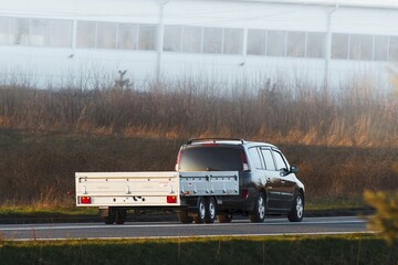 Car towing trailer in sunny countryside
