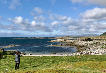Fototapeta premium Woman taking photos on the rugged coastline of Andøya, Norway