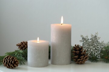 Burning candles and fir branches on white table. Christmas atmosphere