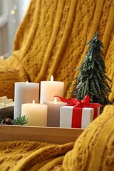 Tray with burning candles and Christmas decor on armchair