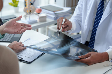 Medical concept Health care and health insurance Male doctor holding x-ray film Explain and give advice on symptoms Abnormal internal organ shapes given to patients at the hospital.