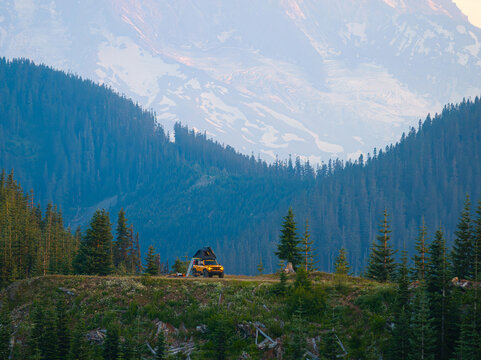 Yellow overlanding truck camping on cliff near Mt. Rainier, Washington