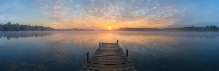 Fototapeta premium Sunrise Over Misty Lake with Wooden Dock