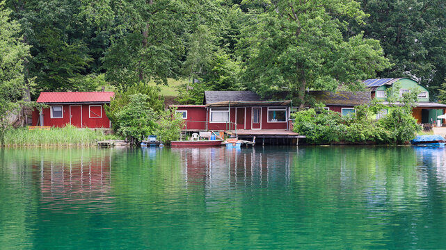 Rote und gr&uuml;ne Ferienh&auml;user am bewaldeten Ufer mit perfekter Wasserspiegelung in smaragdgr&uuml;nem See, Liepnitzsee, Landkreis Barnim, Brandenburg, Deutschland