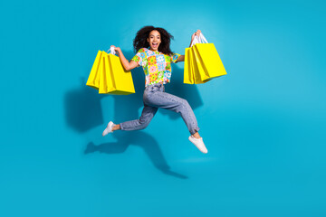 Full length photo of shiny attractive lady dressed flower print t-shirt jumping rising bargains empty space isolated blue color background