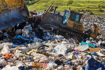 Heavy machinery shredding garbage in an open air landfill. Pollution