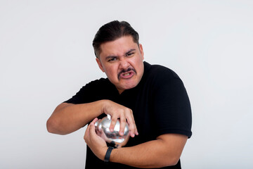 A greedy middle aged man refuses to let go of his piggy bank, clutching with both hands and...