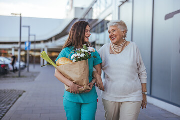 Happy Senior Woman Walking with Caregiver Holding Groceries