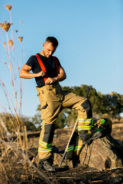 Firefighter Preparing Gear in a Burnt Forest Landscape
