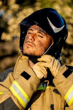 Firefighter adjusting helmet in a sunlit forest setting