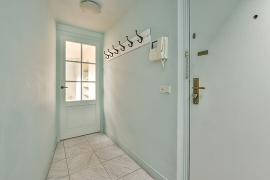 Bright hallway interior with white door and coat hooks