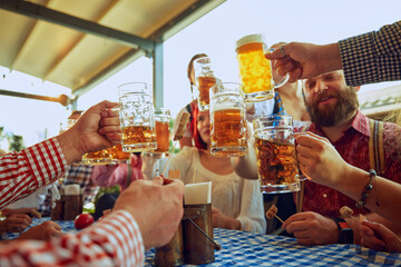 Group of cheerful people, friends, men and women sitting at local pub, drinking beer and having relaxing weekend. Concept of Oktoberfest, festival, party, brewery, traditions