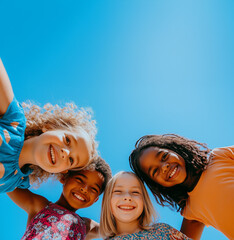 A photo of diverse, happy children looking down at the camera, smiling and posing for an advertising campaign in front of a blue sky. Group portrait of happy kids huddling. Friendship concept.