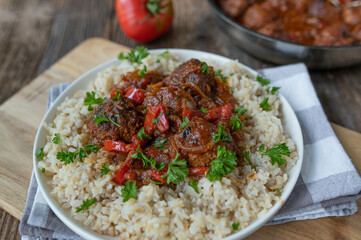 Braised meatballs in a spicy red pepper sauce or puszta sauce on a plate with brown rice