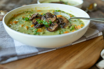 Vegetarian pea soup with pan fried mushrooms. Healthy homemade food on wooden table
