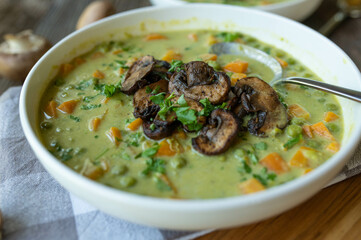 Vegetarian pea soup with pan fried mushrooms. Healthy homemade food on wooden table