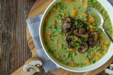 Vegetarian pea soup with pan fried mushrooms. Healthy homemade food on wooden table