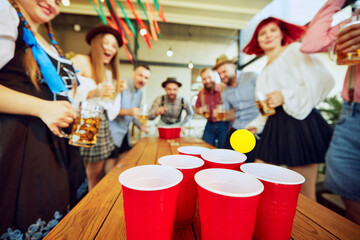 Group of people meeting at pub for beer festival celebration, having fun and playing beer pong. Concept of Oktoberfest, festival, party, brewery, traditions