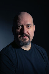 Portrait of a bald mature man with goatee and serious and calm expression, looking at camera on black background. Studio photography. Concept of man, maturity and baldness