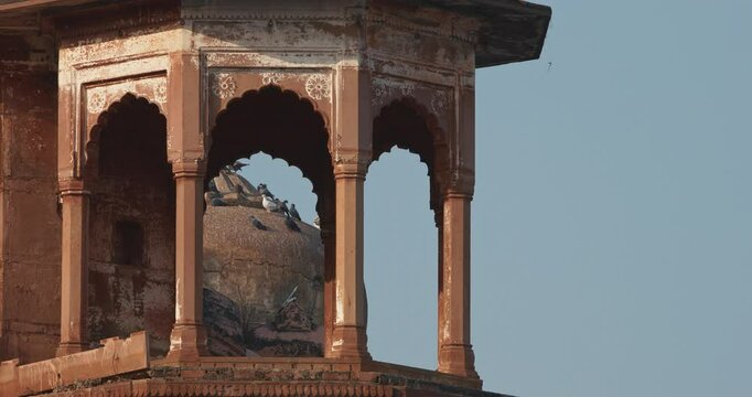 Varanasi, Uttar Pradesh, India. Pigeons Sit On Tower Of Het Singh Fort, Jain Ghat. Clear Blue Sky. Red Wall Of Chet Singh Fort. Slow Motion. Ancient Fort