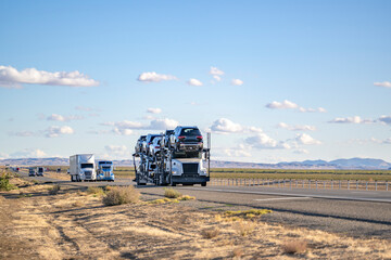 Industrial car hauler big rig semi truck transporting cars on two level semi trailer running on the...