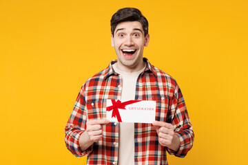 Young surprised shocked happy man he wears red checkered shirt casual clothes hold gift certificate...