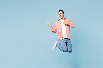 Obraz premium Full body young musician middle eastern man he wear pink shirt white t-shirt jump high point index finger aside on area isolated on plain pastel light blue cyan background studio. Lifestyle concept.