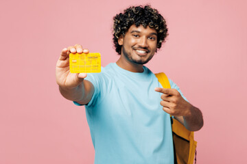 Young smiling smart Indian boy student wear blue t-shirt casual clothes backpack bag hold point on close up credit bank card isolated on plain pink background. High school university college concept. © ViDi Studio