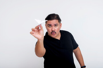 A middle aged man casually launching a paper airplane with his hand. Isolated on a white background.