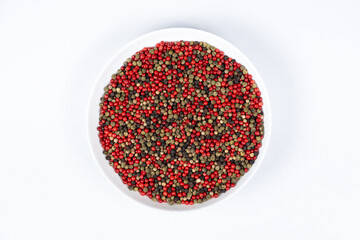 A mixture of different peppercorns on a white background, top view