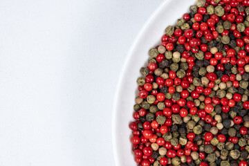 A mixture of different peppercorns on a white background, top view, copy space for text
