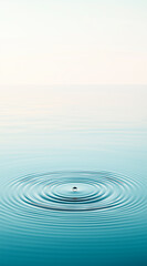 Clear water surface with a single droplet falling into it, creating ripples that spread outward in perfect circular waves. The background is a soft gradient of light blue and white