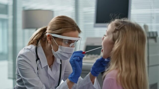 Doctor taking throat swab in medical clinic closeup. Woman professional in mask