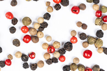 Red, green, white and black peppercorns on a white background macro top view.