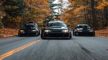 Fototapeta premium Black Sports Cars Driving Through Fall Foliage on a Winding Road