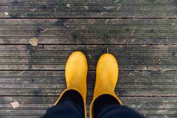 Yellow rubber boots. Woman in yellow rubber boots close-up on pier in autumn Finland.