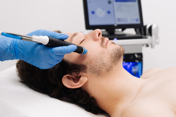 A man undergoes hydrofacial vacuum facial cleansing, rejuvenation, moisturizing facial procedure in...