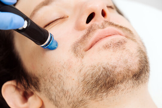 A man undergoes hydrofacial vacuum facial cleansing, rejuvenation, moisturizing facial procedure in a beauty clinic. Beauty and youth concept