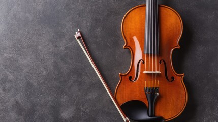 Fototapeta premium Close-up view of a violin and bow on a textured surface, highlighting the instrument's craftsmanship and elegance.