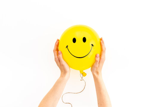 Happy smiling yellow balloon in hand. Happiness emotions concept