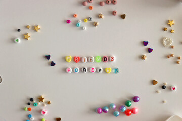 Friends forever written with colorful beads. Jewelry making supplies on the table. Making friendship bracelets concept. Flat lay.
