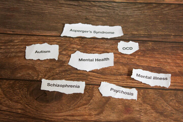 Mental health disorders on strips of paper on wooden table. 