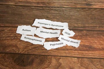 Mental health disorders on strips of paper on wooden table. 