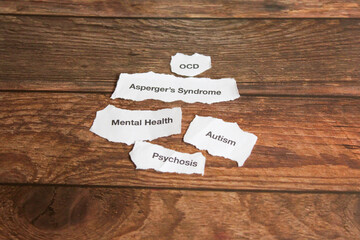 Mental health disorders on strips of paper on wooden table. 