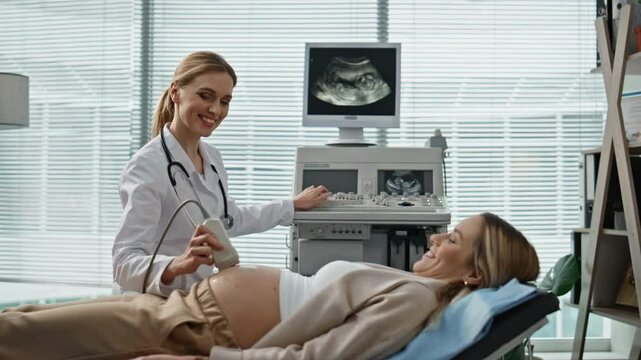 Doctor performing ultrasound pregnant woman in clinic. Happy patient on couch