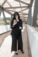 Confident Businesswoman with Smartphone Standing on Modern Urban Bridge