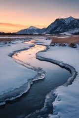 Fototapeta premium a half-frozen icy river leading to mountains at the far end