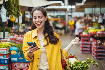 Happy Woman Shopping at Farmers Market While Using Smartphone